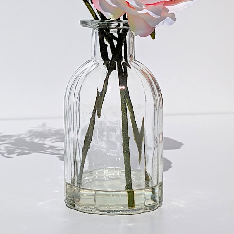 Focus sur le vase : Détail du vase en verre cannelé montrant la résine transparente emprisonnant les tiges.