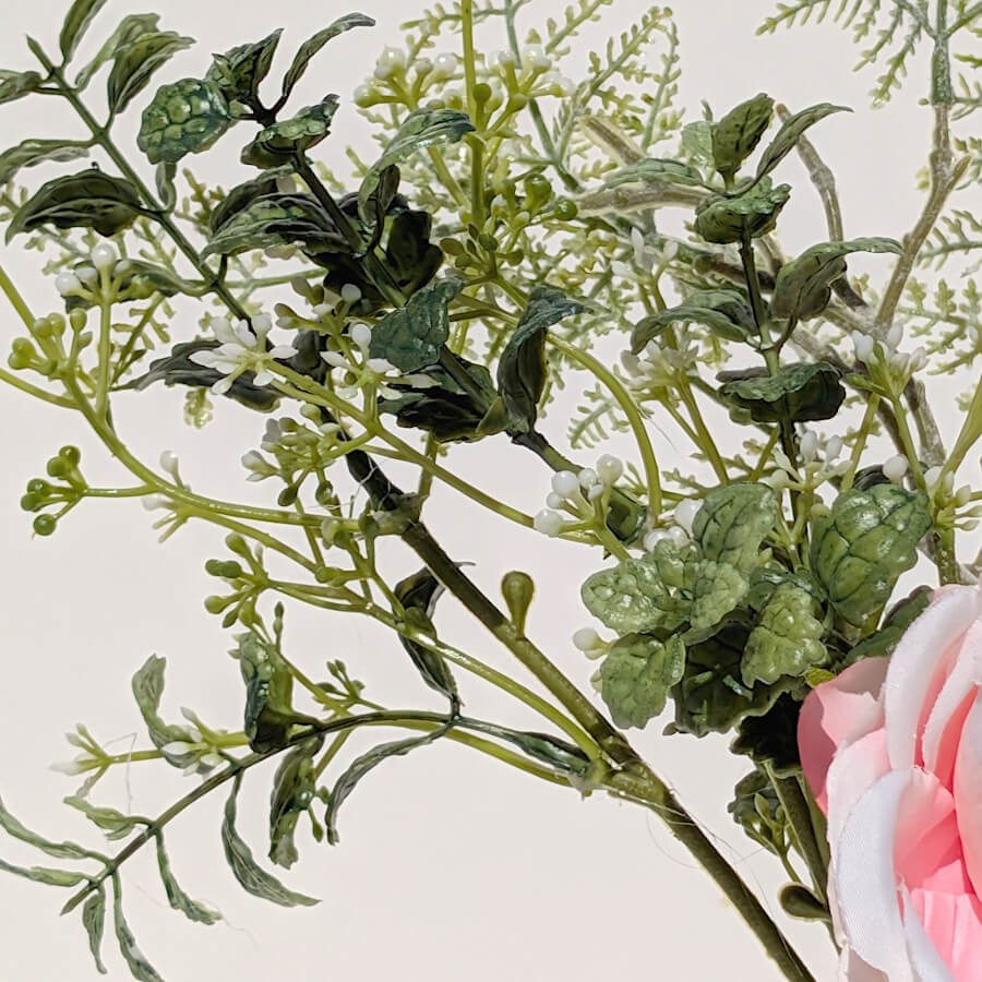 Détail du feuillage : Gros plan sur les branches d'eucalyptus et les petites fleurs blanches accompagnant les roses.