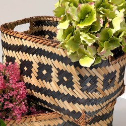 Le panier en bambou tressé garni de fleurs d'hortensias verts et de fleurs roses sur fond clair.