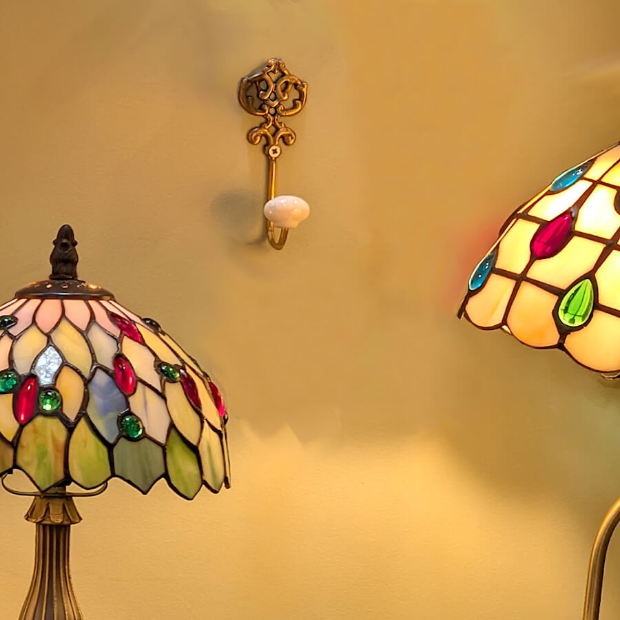 La patère murale intégrée dans un décor vintage feutré, entourée de deux lampes de style Tiffany allumées.