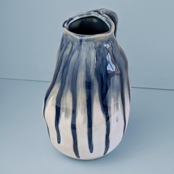 Vue de face : Pichet en céramique à effet de coulures bleues sur fond bleu.