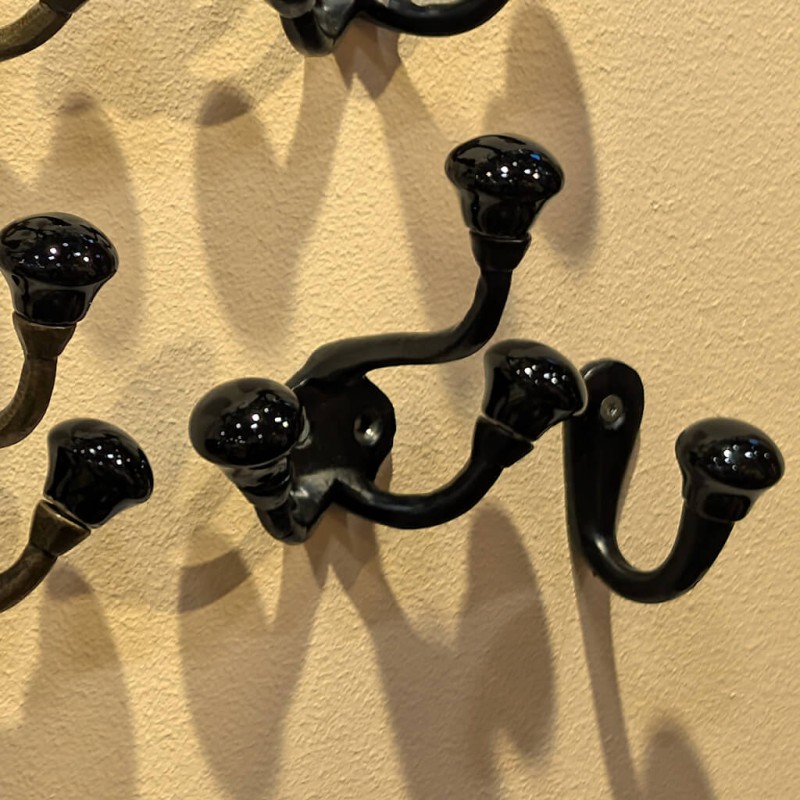 Jeu d'ombres : Ombre portée de la patère noire sur un mur clair baigné de lumière.