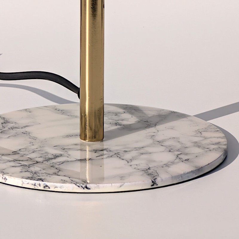 Zoom socle : Base circulaire en marbre blanc veiné et raccord de tige dorée.