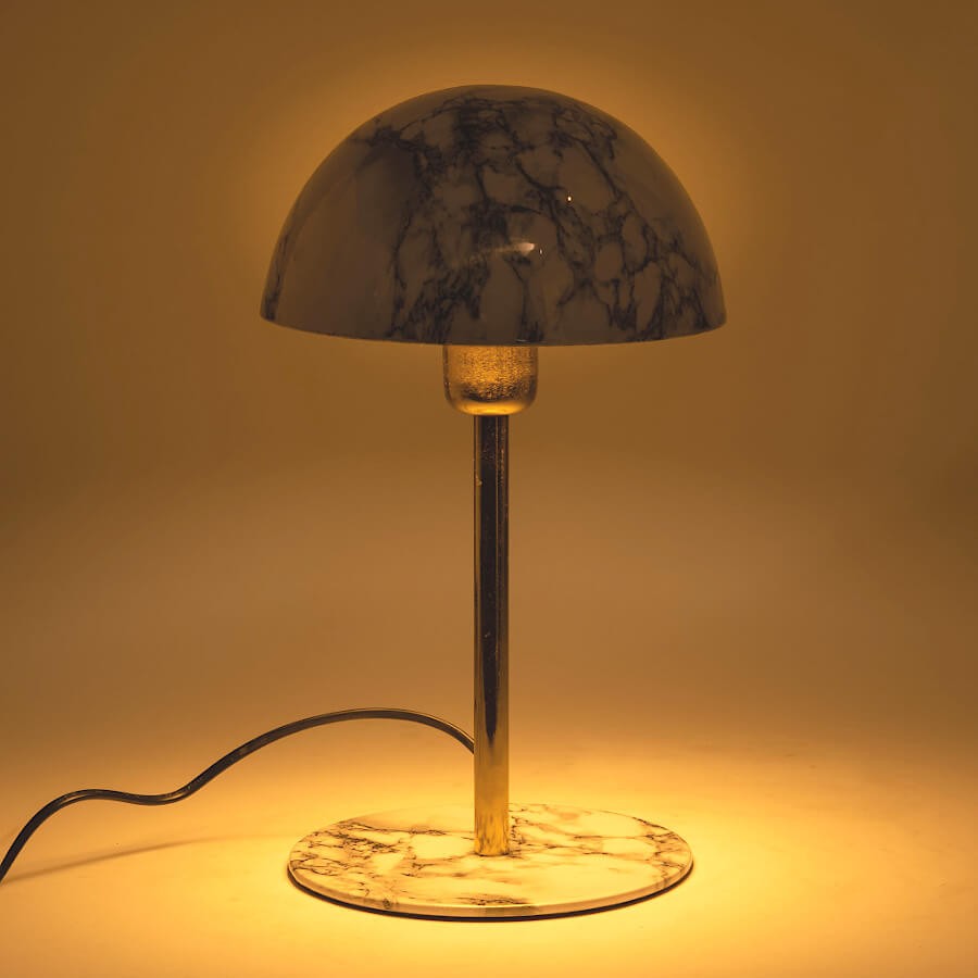 Vue allumée : Lampe champignon en marbre diffusant une lumière chaude et tamisée.