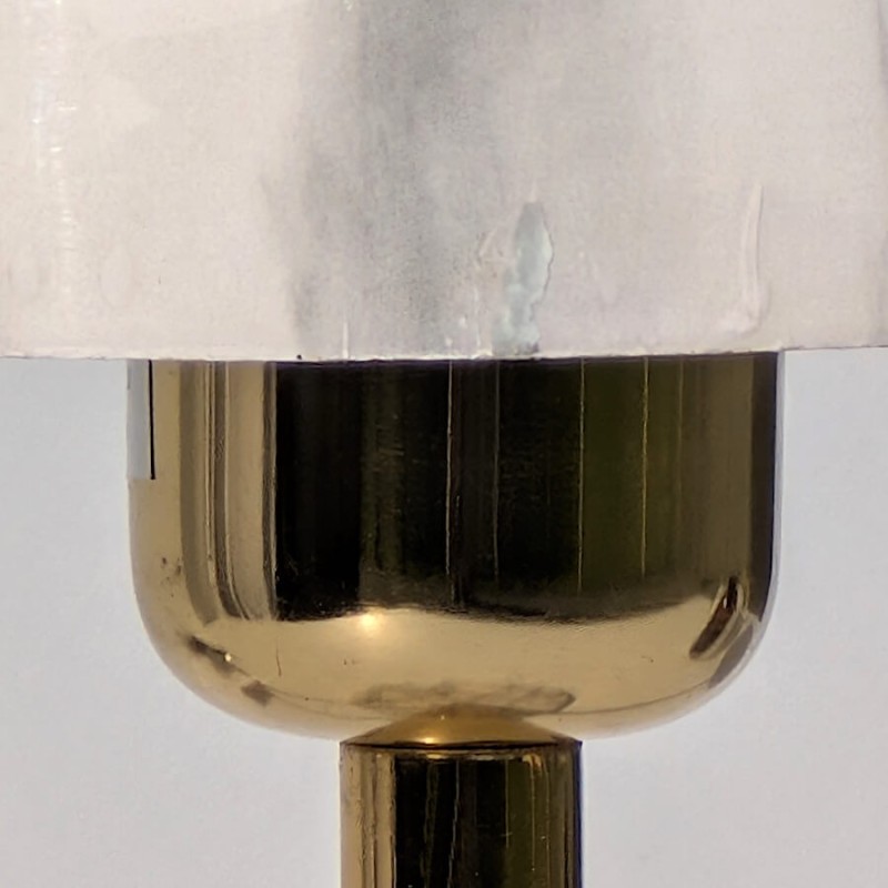 Zoom col de lampe : Gros plan sur la douille en laiton doré brillant sous le dôme en marbre.