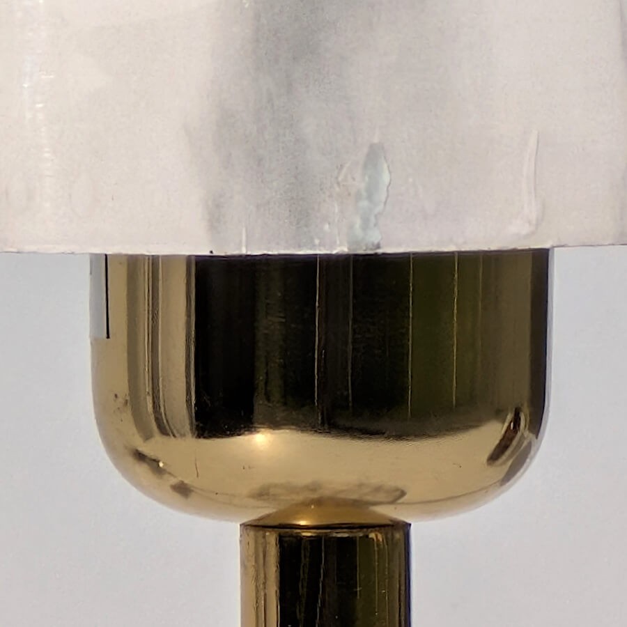 Zoom col de lampe : Gros plan sur la douille en laiton doré brillant sous le dôme en marbre.