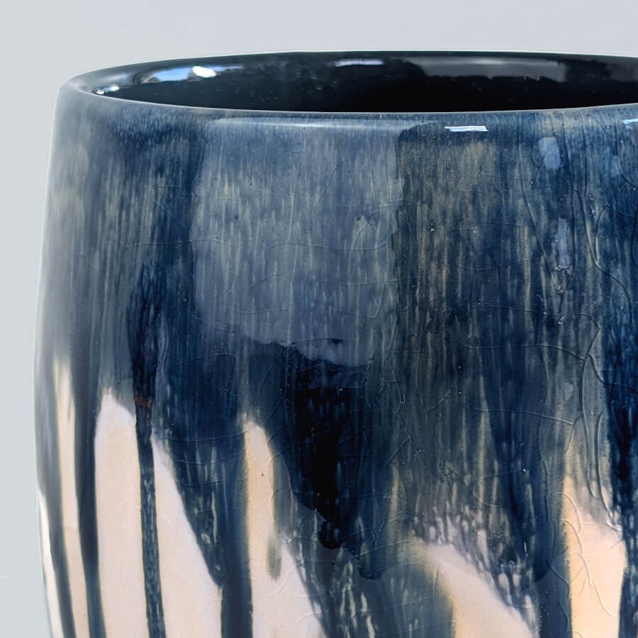Zoom glaçure : Détail des coulures bleu marine et des nuances rosées de l'émail brillant.