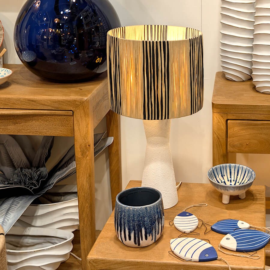 Mise en scène : Cache-pot en céramique sur un meuble en bois à côté d'une lampe dorée.