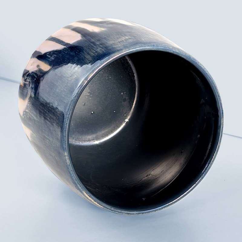Vue plongeante : Regard intérieur sur la cavité noire et lisse du pot en céramique.