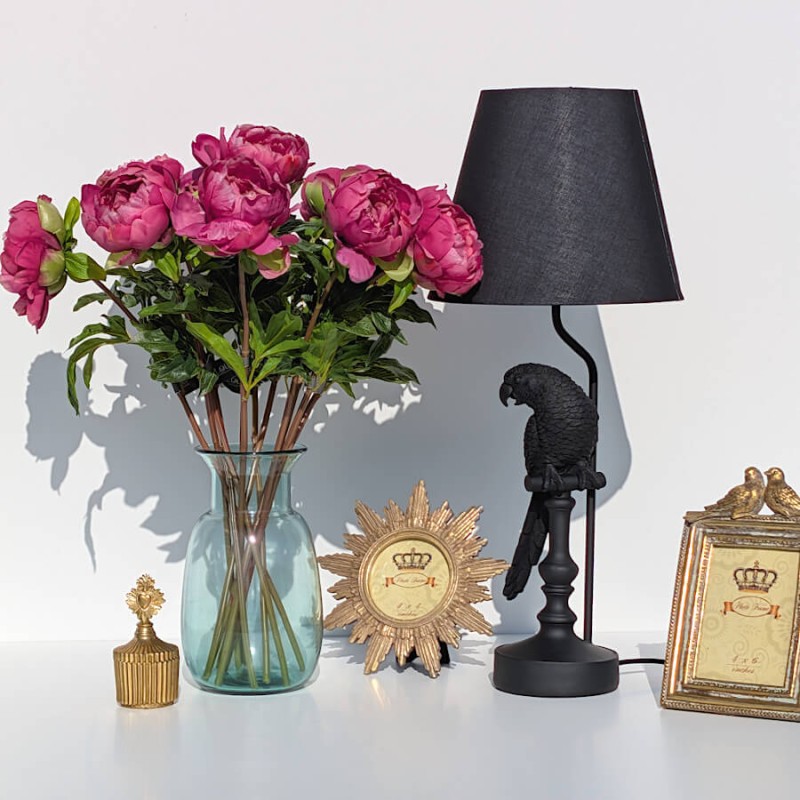 Mise en scène romantique : Bouquet de pivoines à côté d'une lampe Perroquet noire et d'un cadre doré.