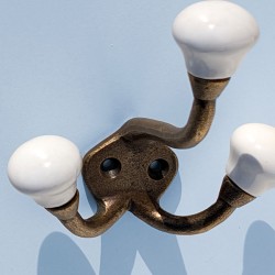 Vue de face : Structure à triple branche dorée surmontée de cabochons en faïence blanche.