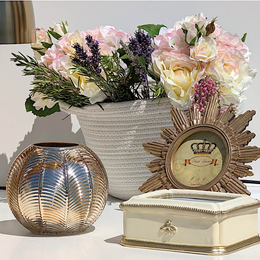 Vue de situation lumineuse : Bougeoir rond argenté et doré sur une table avec boîte à bijoux et fleurs Deco-Delight.