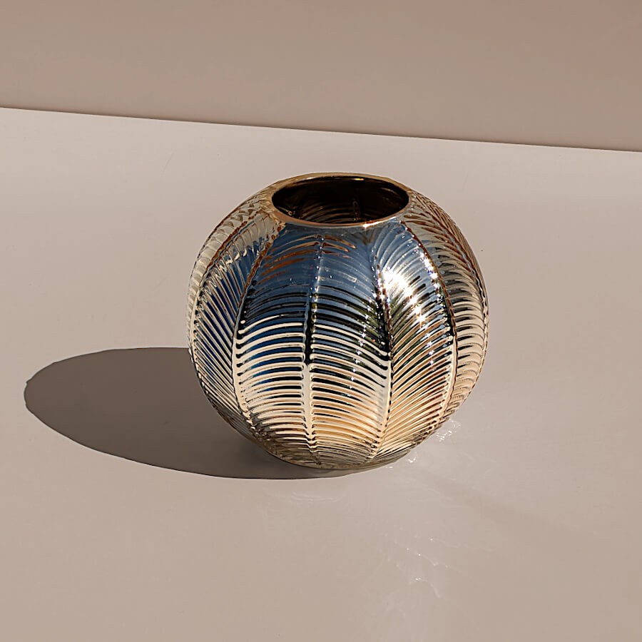 Jeu d'ombre portée : Photophore rond en verre métallisé posé sur une surface blanche au soleil.