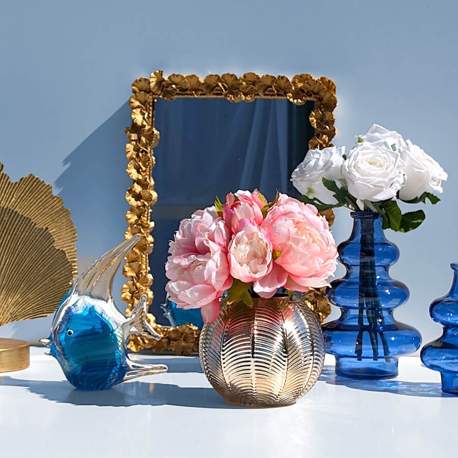 Harmonie colorée : Petit vase boule doré garni de pivoines roses à côté du miroir Gingko sculpté.