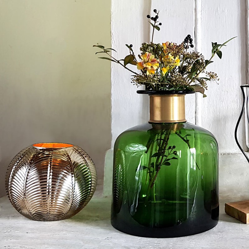 Composition naturelle : Duo de vases en verre vert bouteille et photophore doré sur une cheminée en pierre.