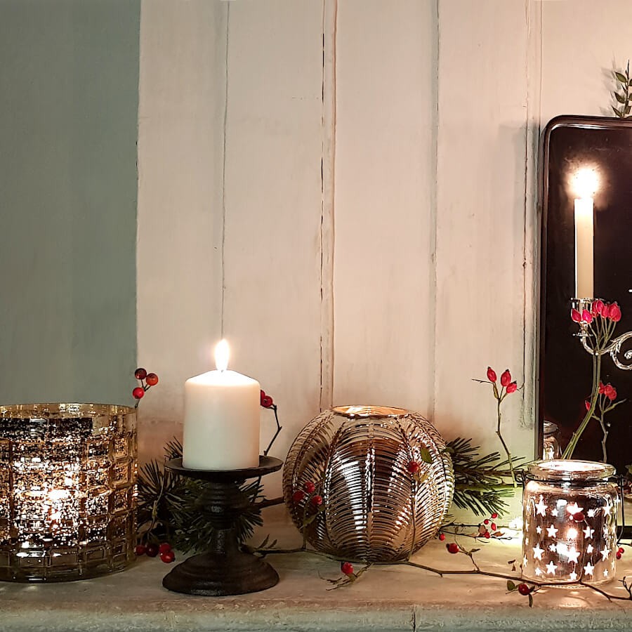 Décoration de Noël cosy : Grosse bougie pilier blanche et photophore sphérique doré illuminés.
