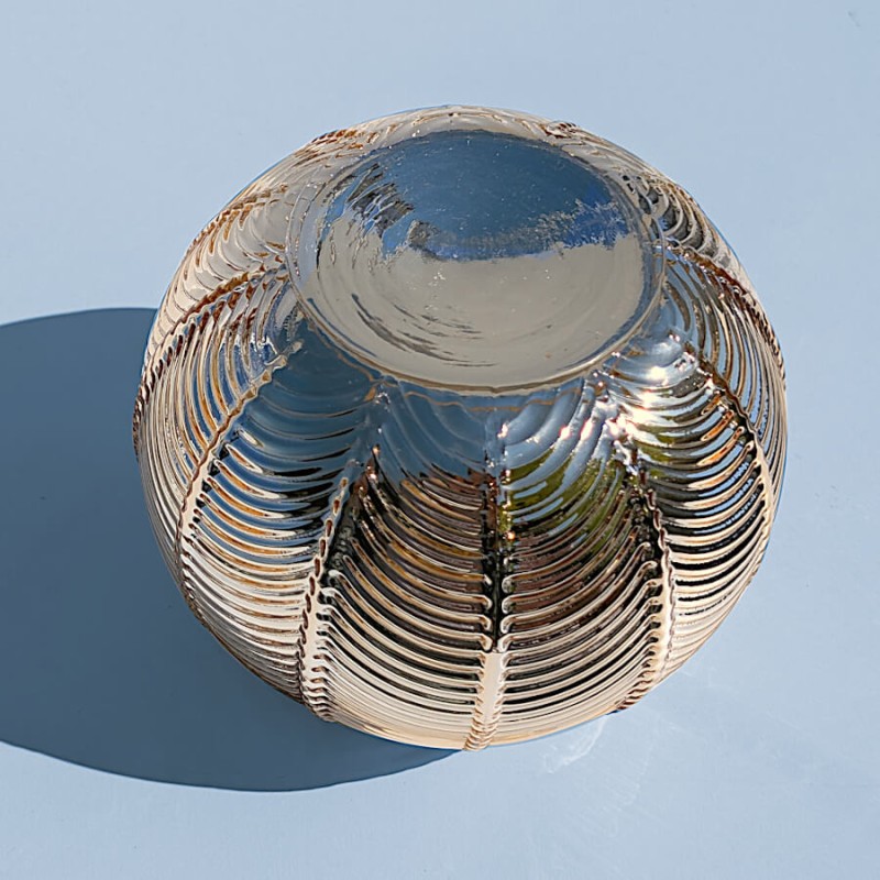 Vue de dessous : Base stable et lisse du photophore sphérique en verre teinté or.
