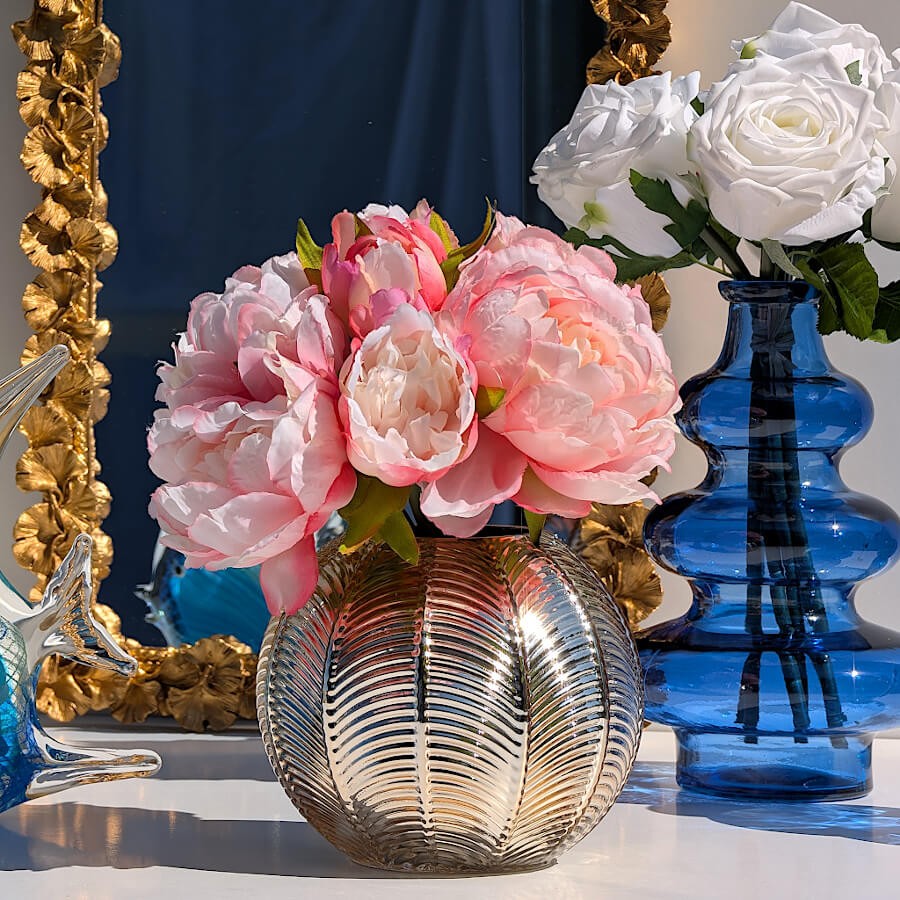 Zoom fonction vase : Pivoines roses artificielles disposées à l'intérieur du photophore boule doré utilisé comme vase.