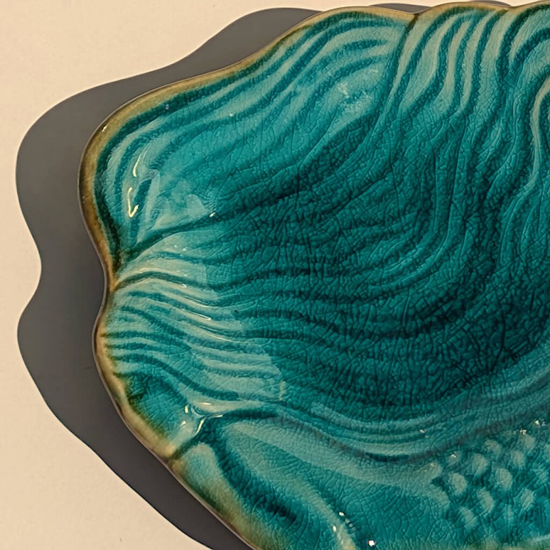 Gros plan texture : Détail des reliefs sculptés et des nuances de la glaçure craquelée turquoise.