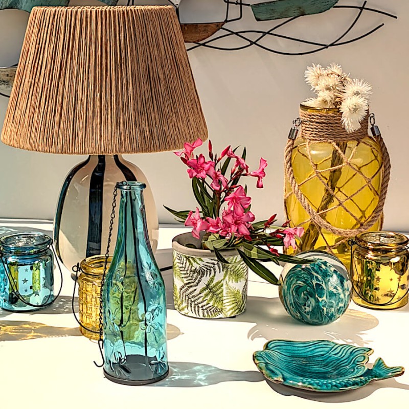 Style Vacances ensoleillées : Pot en ciment associé à une lampe en raphia, une bouteille en verre bleu et un plat sirène.