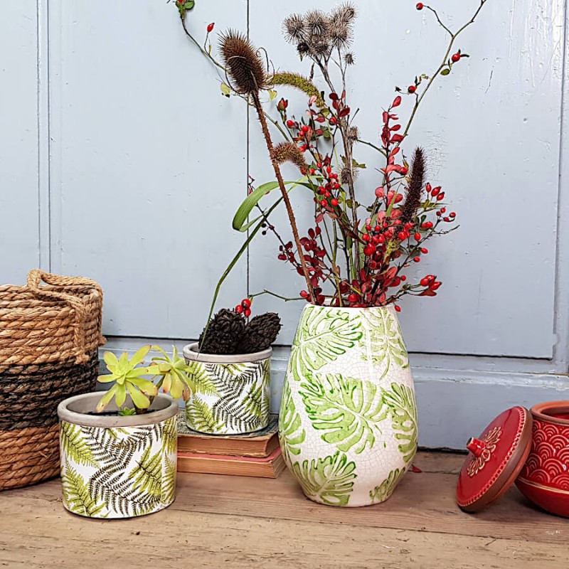 Mise en scène campagne : Petit pot en ciment posé sur de vieux livres à côté d'un vase floral.