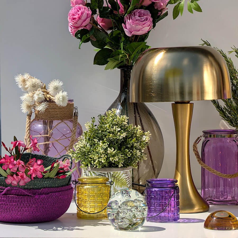 Composition colorée : Pot imprimé de fougères associé à des photophores violets et une lampe dorée.