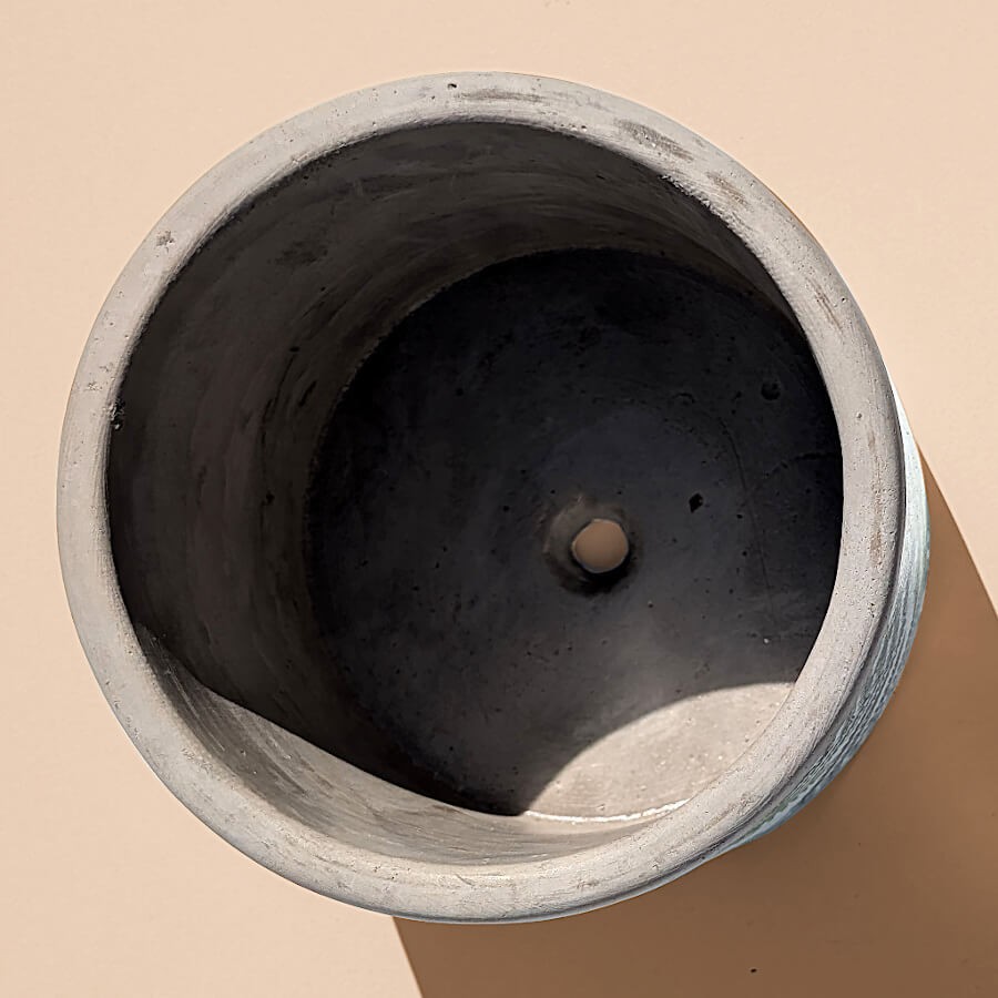 Vue de dessus : Intérieur gris du pot en ciment avec le trou de drainage central bien visible.