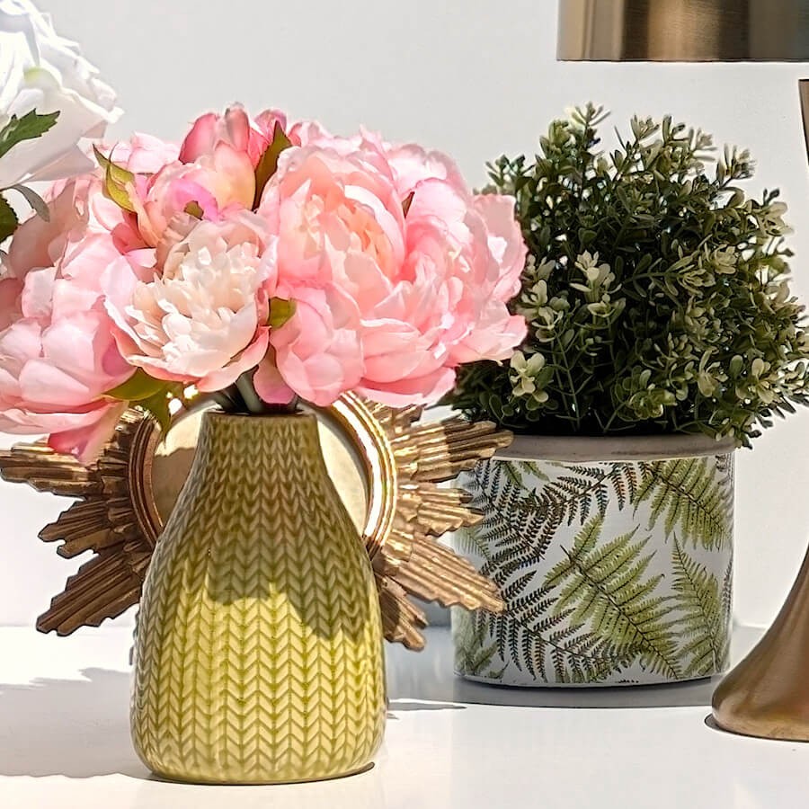 Harmonie florale : Cache-pot végétal disposé en arrière-plan d'un vase jaune garni de pivoines roses.