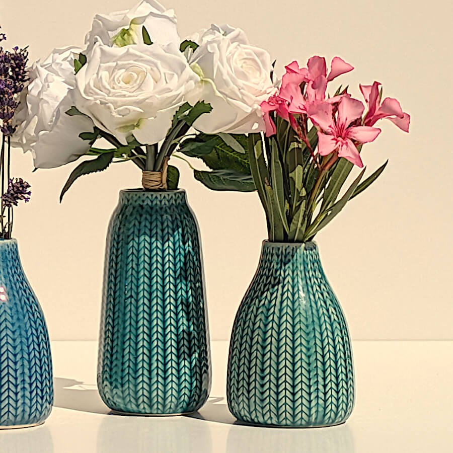 Duo de fleurs : Vases épi bleu et turquoise garnis de fleurs blanches et fushia.