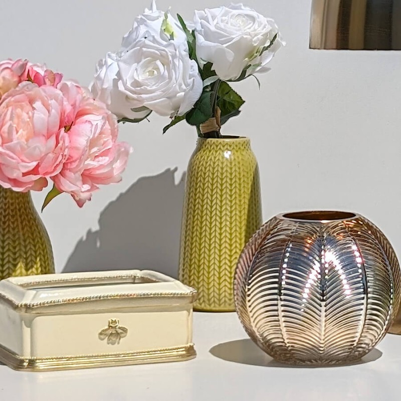 Ambiance Tropicool : Vase jaune avec pivoines roses à côté d'une lampe champignon dorée et d'un perroquet vert Deco-Delight.
