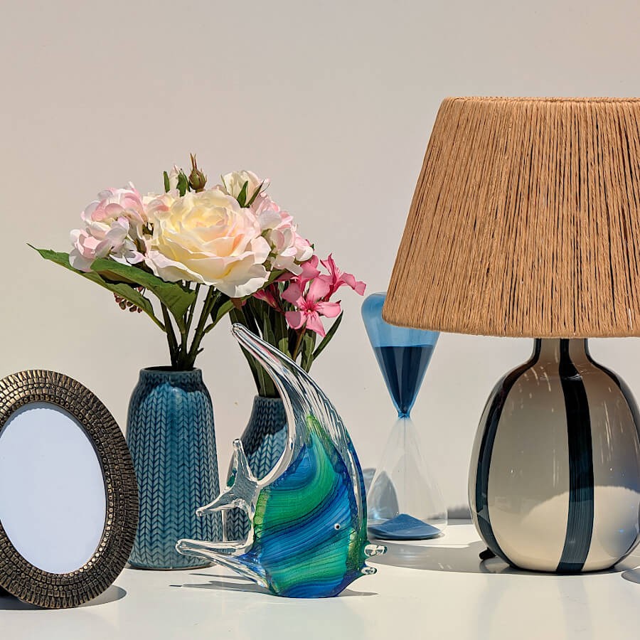 Table Océane : Vase bleu épi associé à une lampe abat-jour en raphia, et des accessoires marins en verre soufflé.