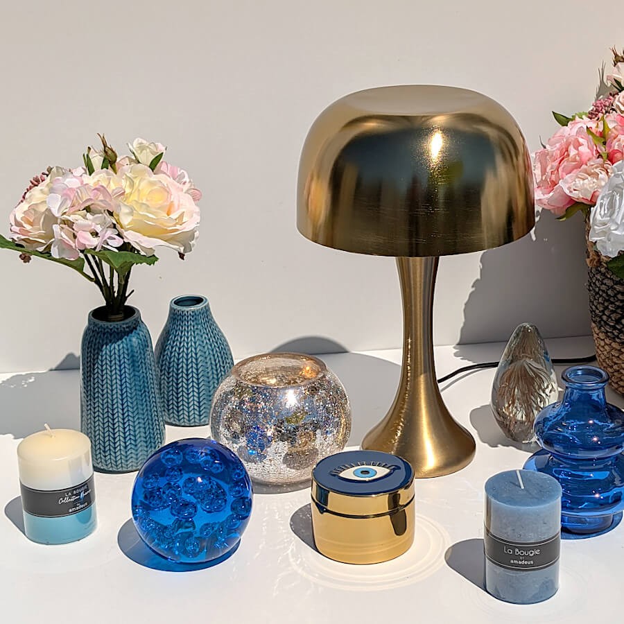 Mise en scène bord de mer : Vase bleu entouré de bougies, de photophores azur et d'une lampe dorée Deco-Delight.