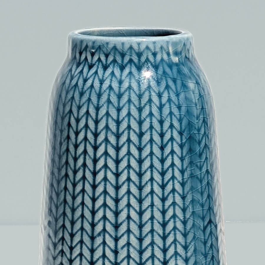 Gros plan col bleu : Zoom sur le col resserré et les motifs géométriques du vase bleu.