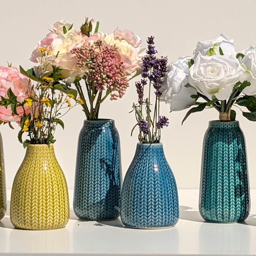 Harmonie de couleurs : Vases jaune, bleu et turquoise garnis de fleurs roses, blanches et lavande.