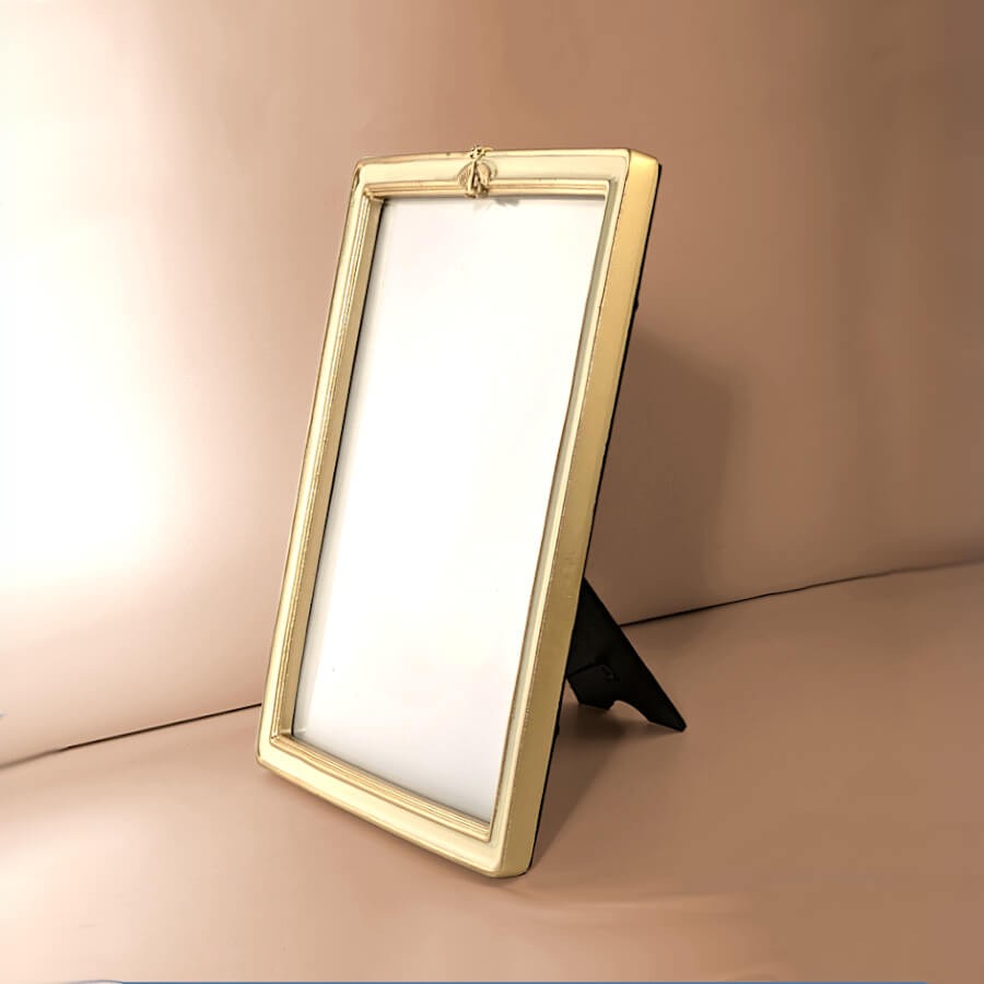 Vue de profil lumineux : Cadre de table crème et or incliné montrant son pied de support noir.