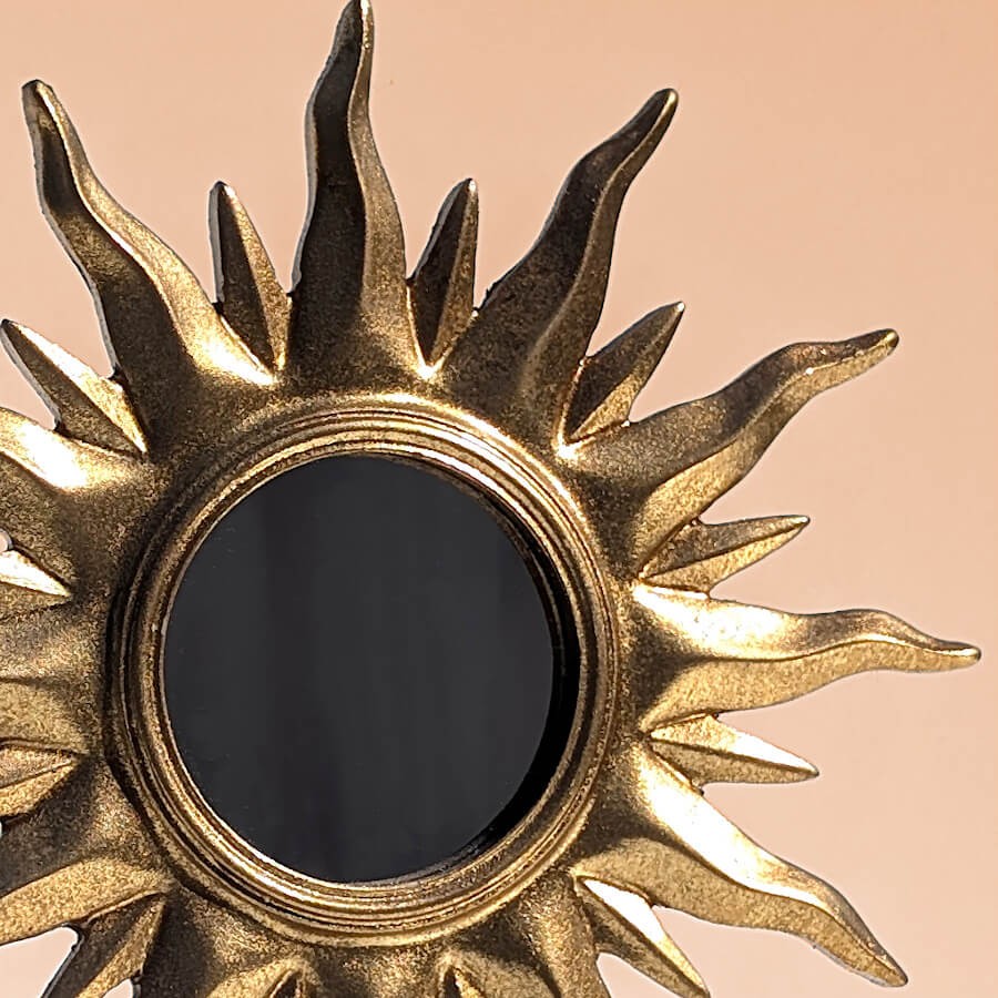 Gros plan cadre : Zoom sur les détails sculptés des rayons solaires et la finition dorée patinée.