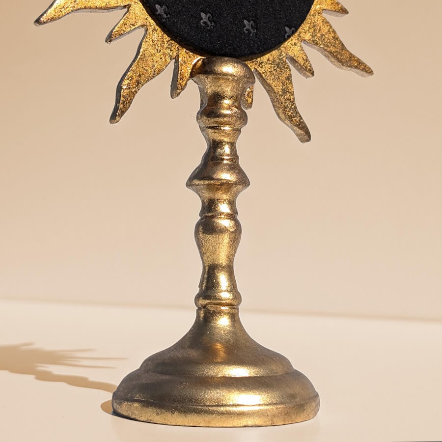 Zoom pied sculpté : Focus sur la tige élancée et moulurée du miroir de table soleil or.
