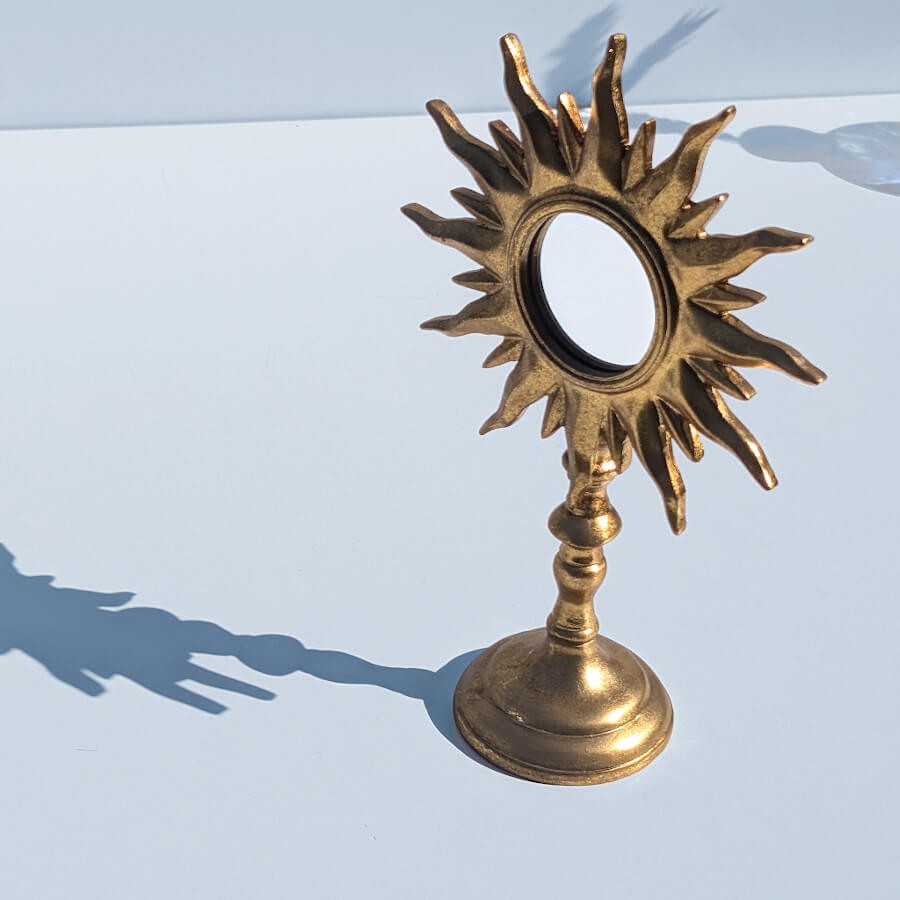 Jeu d'ombres : Silhouette graphique du miroir soleil projetant son ombre sur un fond blanc épuré.