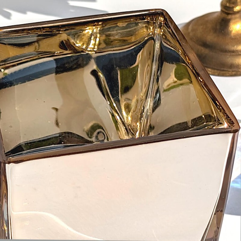 Zoom sur l'angle et les reflets intérieurs du modèle doré sous une lumière vive.