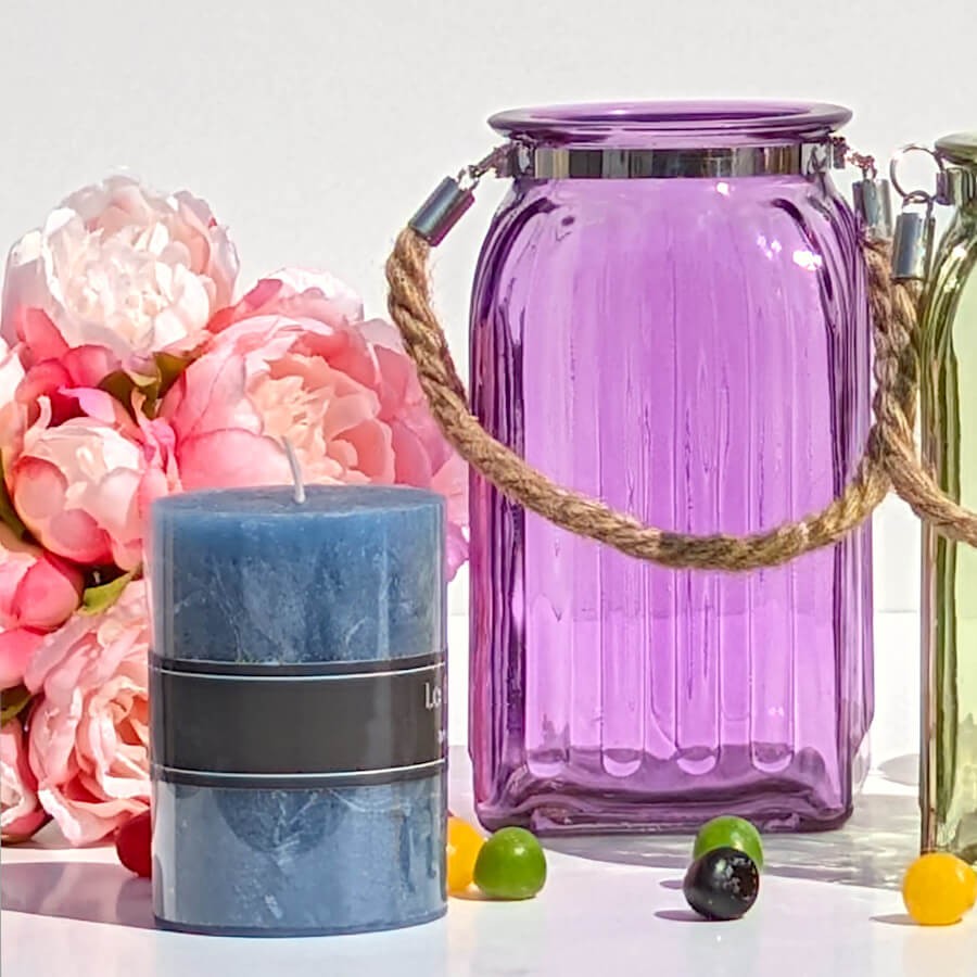 Ambiance florale : Lanterne violette à côté d'une bougie pilier bleue et de pivoines roses Deco-Delight.