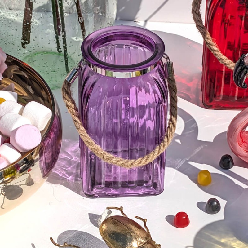 Table de fête : Duo de lanternes violettes disposées sur une nappe blanche parmi des confiseries colorées.