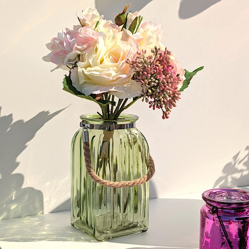 Esprit bucolique : Le photophore vert tressé utilisé comme vase pour accueillir un bouquet de fleurs printanières.