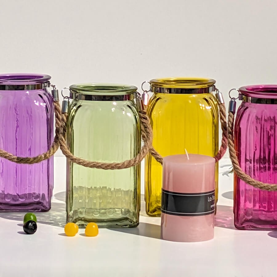 Alignement bohème : Lanternes violette, verte et jaune accompagnées d'une bougie rose poudré.