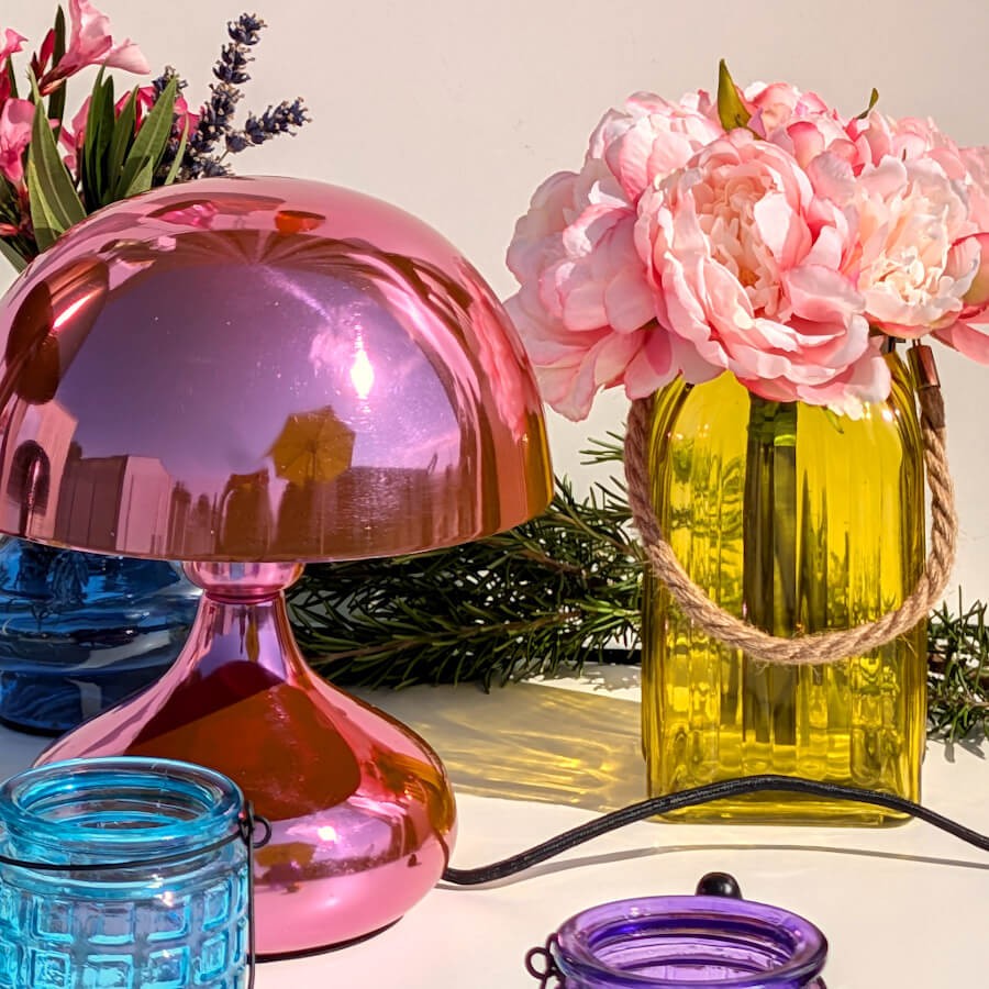 Ambiance pop rose : Photophore jaune utilisé comme vase avec pivoines à côté d'une lampe champignon rose métallisé.