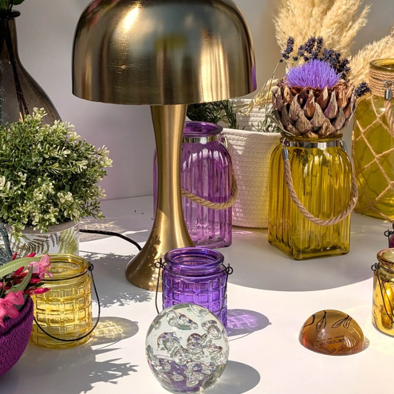 Table basse déco chic : Centre de table associant la lampe champignon dorée aux photophores jaune et violet.