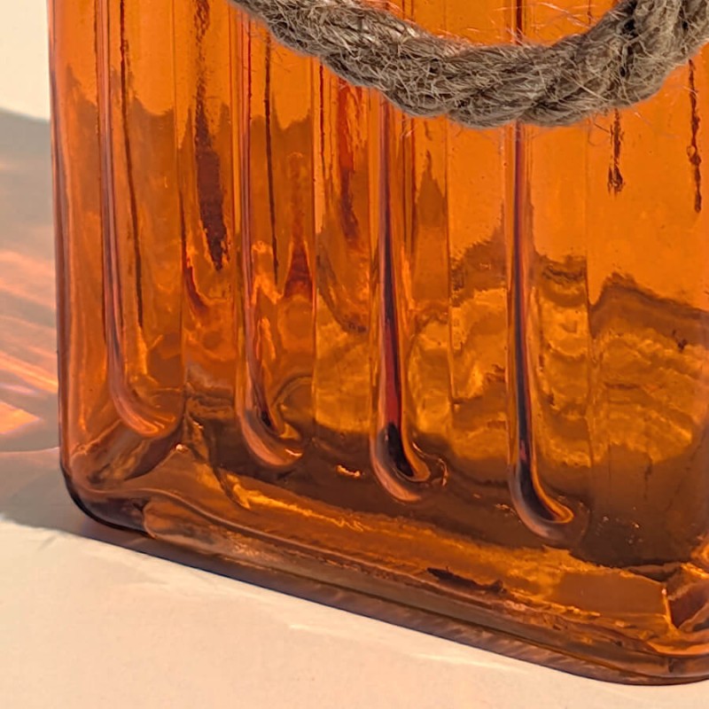 Focus relief cannelé : Détail des rayures verticales gravées dans le verre teinté orange translucide.