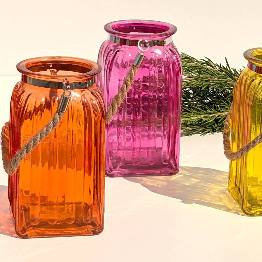Duo contrasté : Photophore en verre orange à côté du modèle de lanterne rose fuchsia translucide.