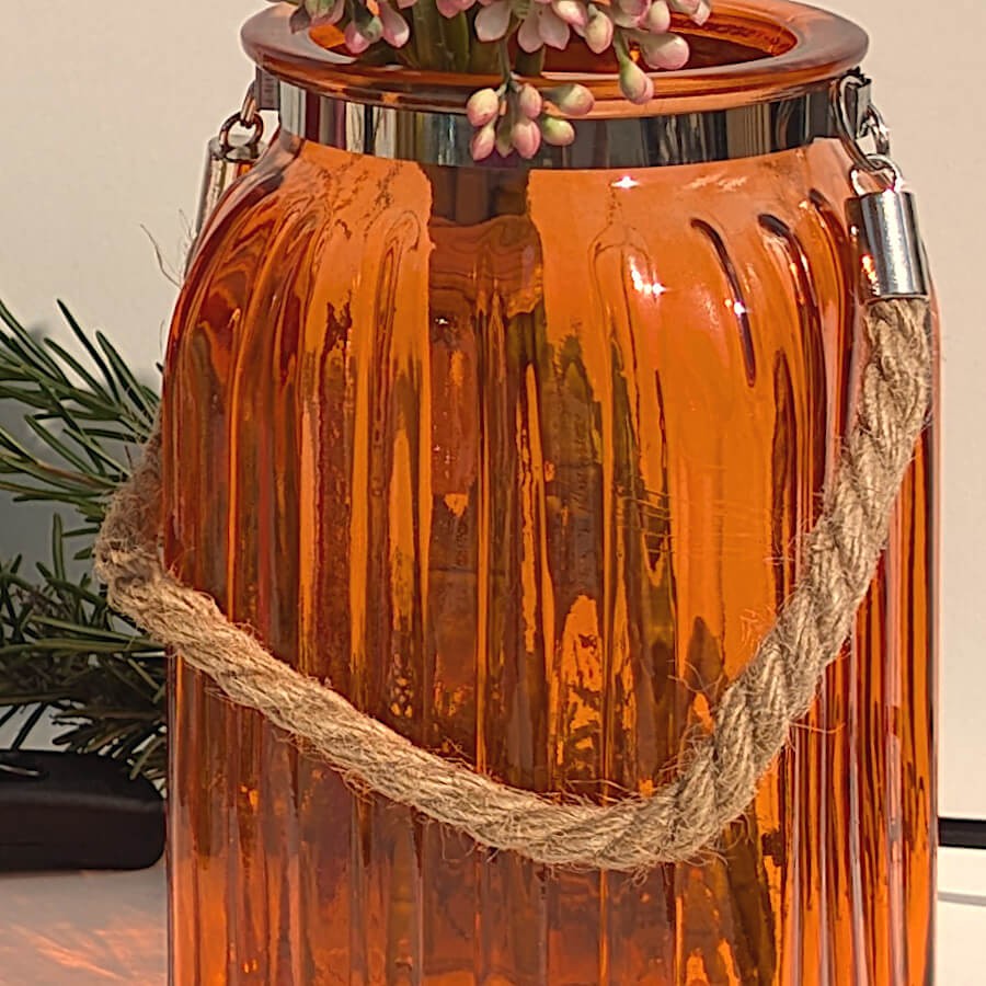 Plan rapproché sur la lanterne en verre orange avec sa corde.