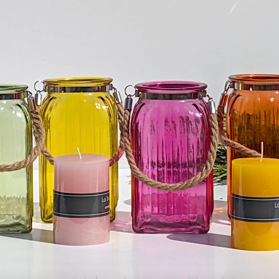 Alignement multicolore : Collection de photophores colorés entourant deux bougies piliers (rose et jaune hydromel).
