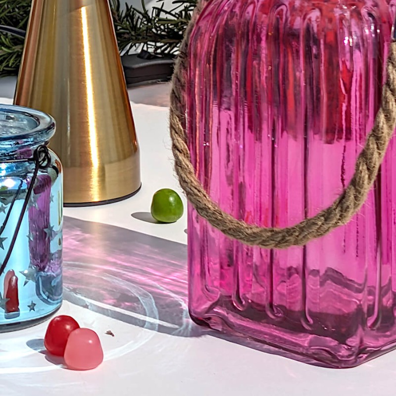 Reflets solaires : Les ombres colorées et texturées de la lanterne rose fuchsia projetées sur une surface blanche.